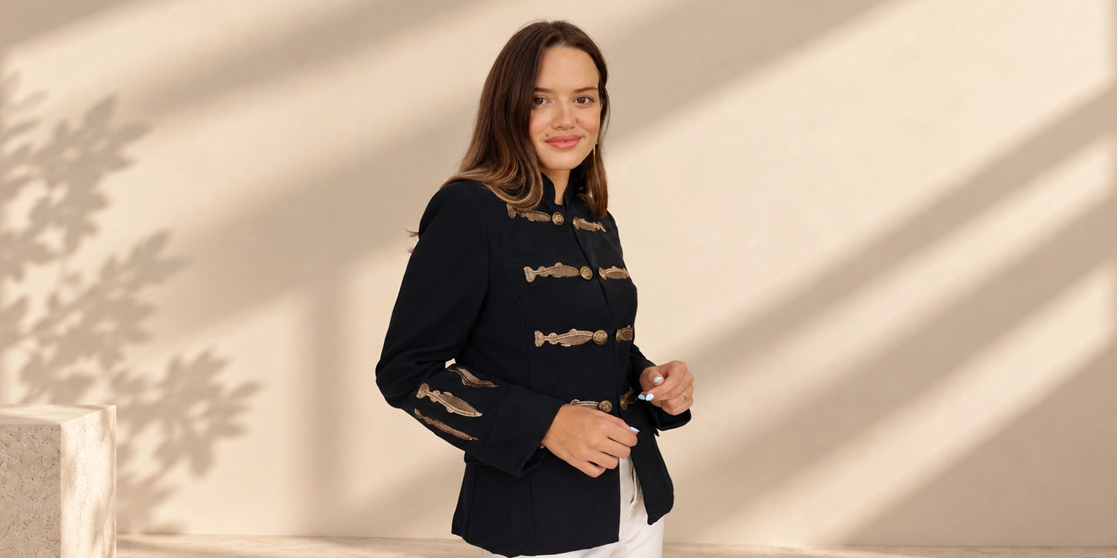 Modelo de moda femenina con chaqueta azul marino y bordados dorados de Panttac