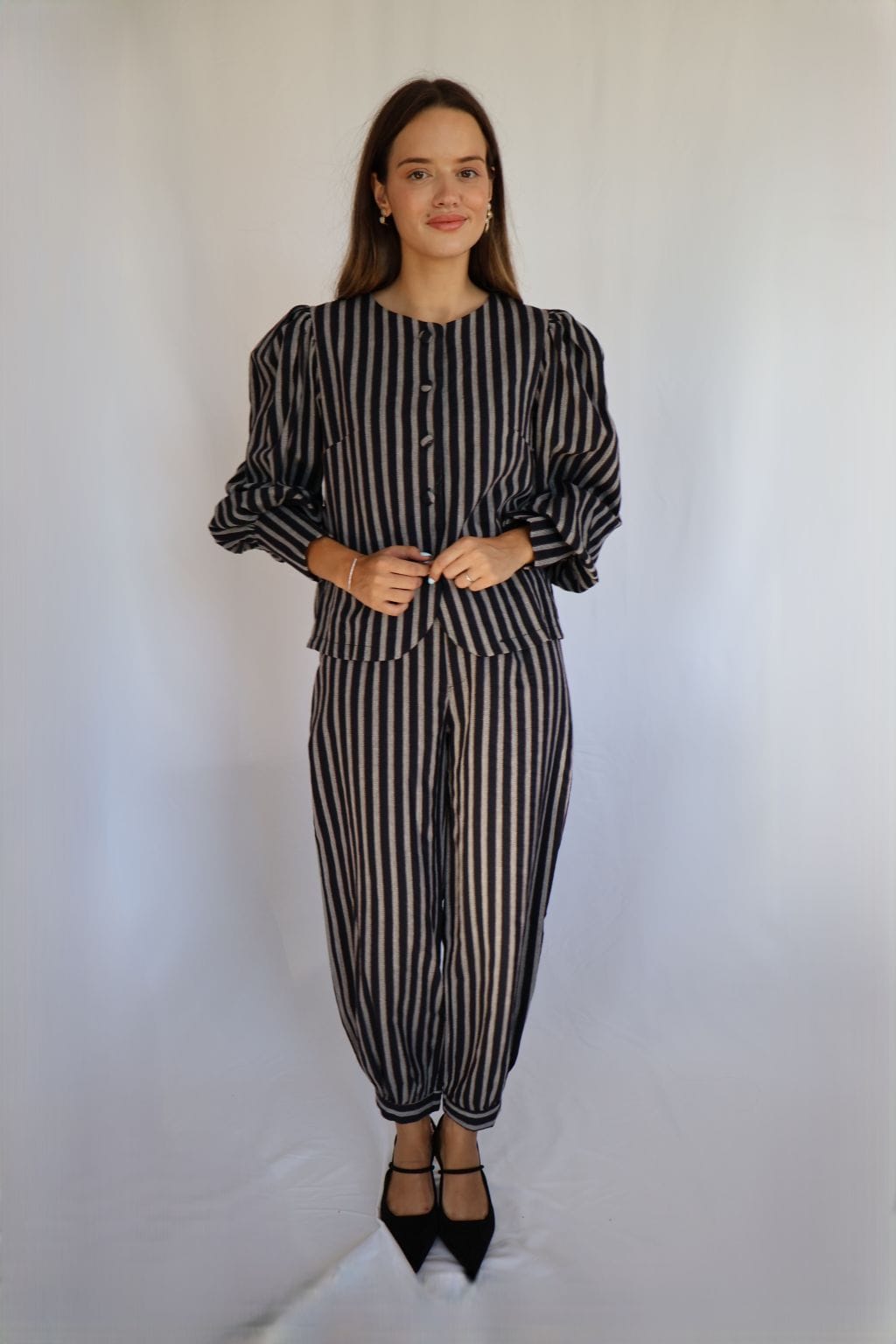 Mujer con pantalón de rayas azul marino y crudo combinado con chaqueta de mangas abullonadas a juego.