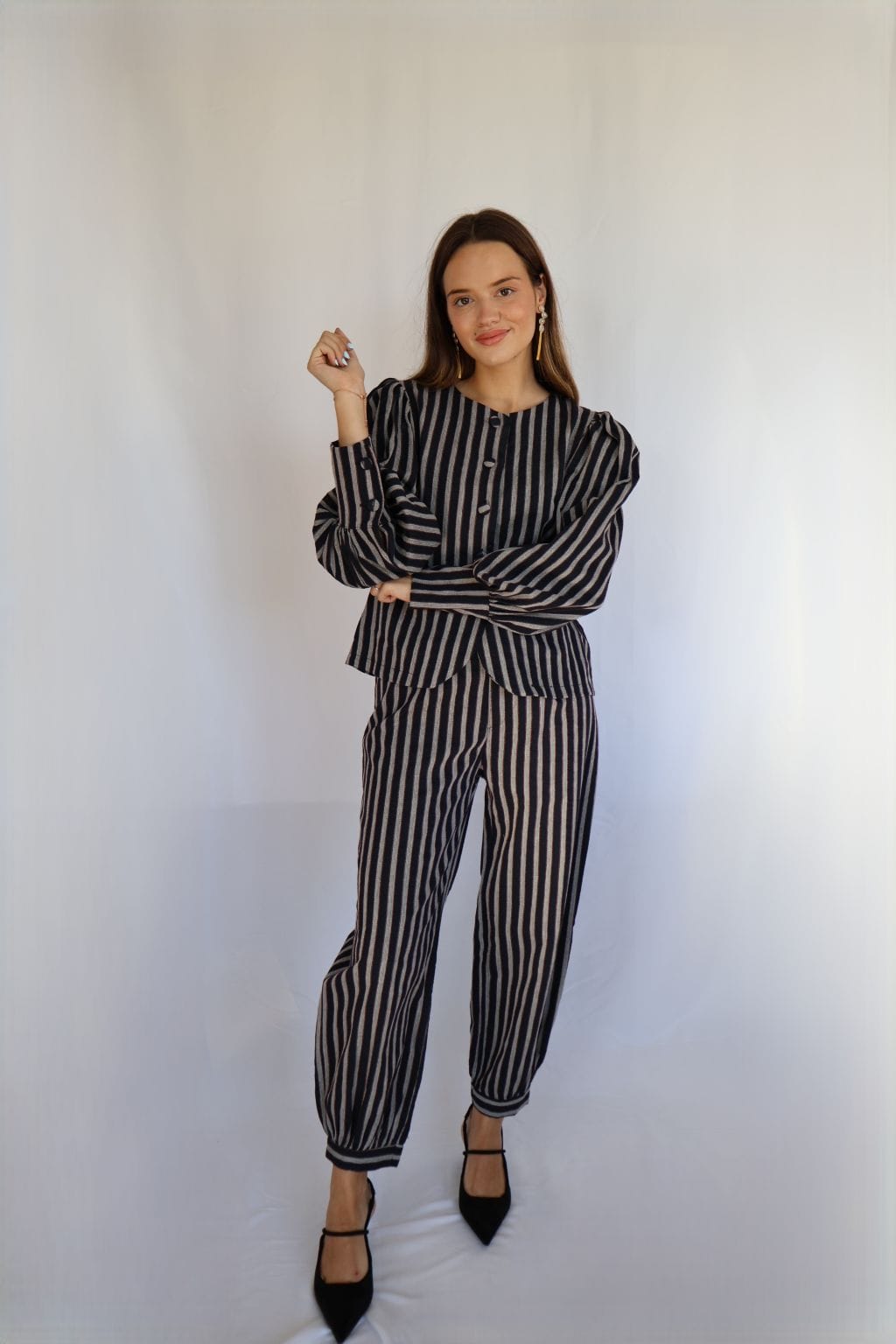 Mujer con pantalón de rayas azul marino y crudo combinado con chaqueta de mangas abullonadas a juego.