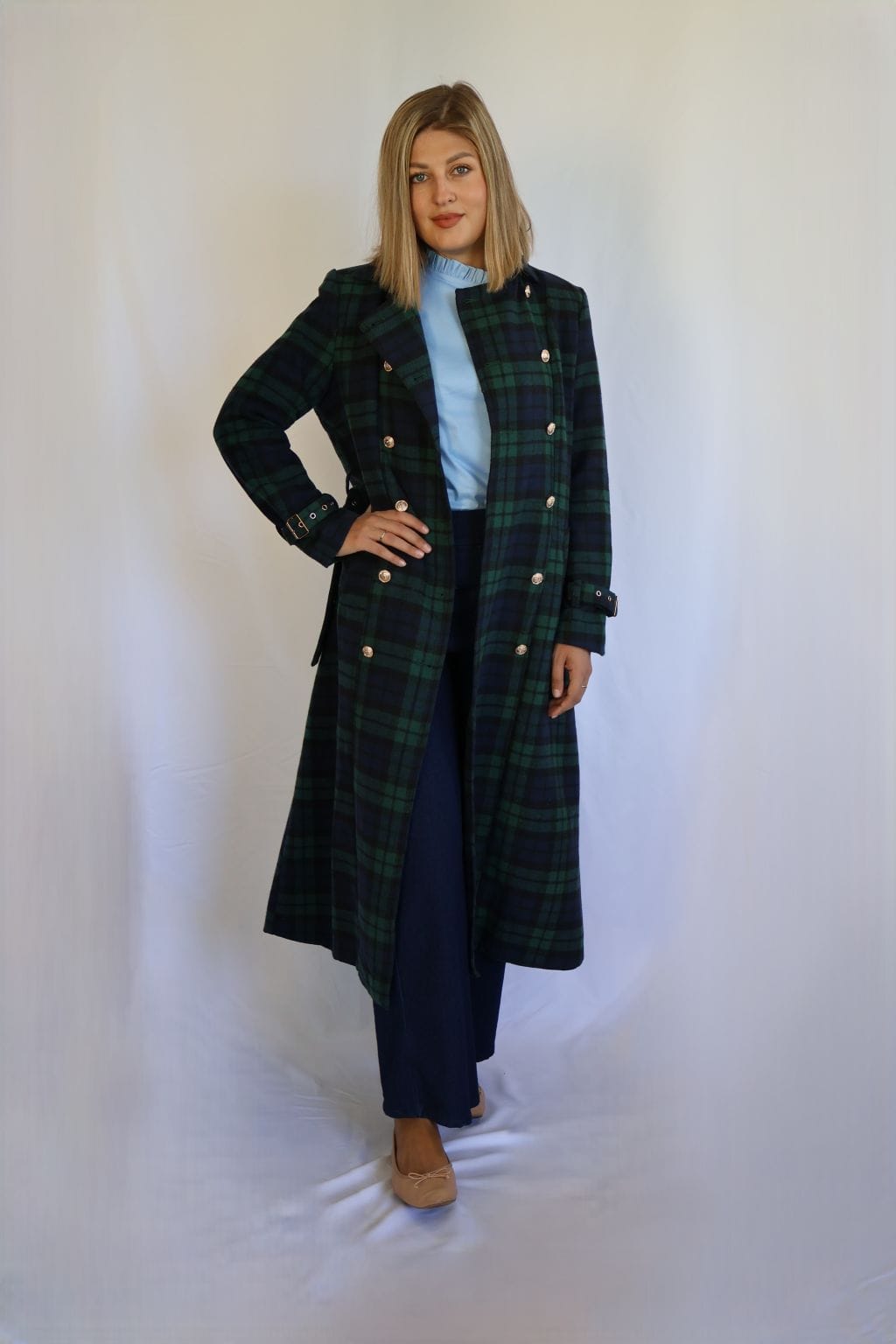 Abrigo largo de cuadros verde y azul marino para mujer, con cierre cruzado de botones dorados, cinturón con hebilla y puños ajustables.