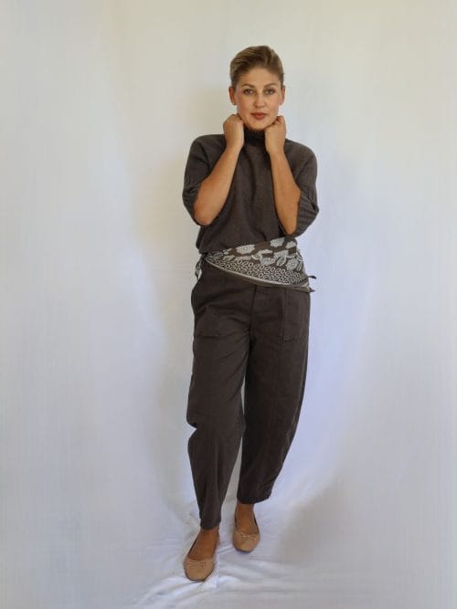 Jersey de punto marrón de mujer con manga corta hasta el codo y cuello chimenea de canalé, combinado con pantalón marrón y cinturón estampado.