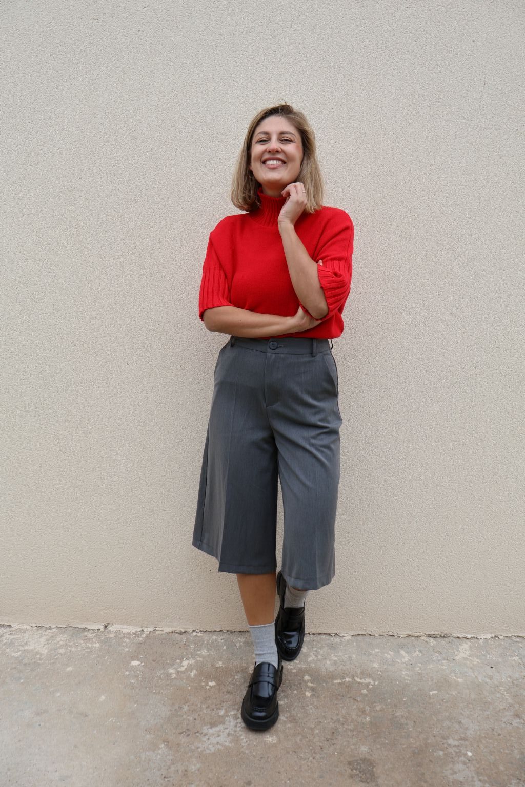 Bermuda gris de mujer PANTTAC de corte ancho, con bolsillos y largo por debajo de la rodilla, combinada con jersey rojo y mocasines negros.