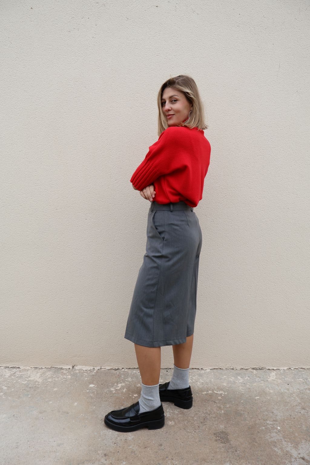 Bermuda gris de mujer PANTTAC de corte ancho, con bolsillos y largo por debajo de la rodilla, combinada con jersey rojo y mocasines negros.