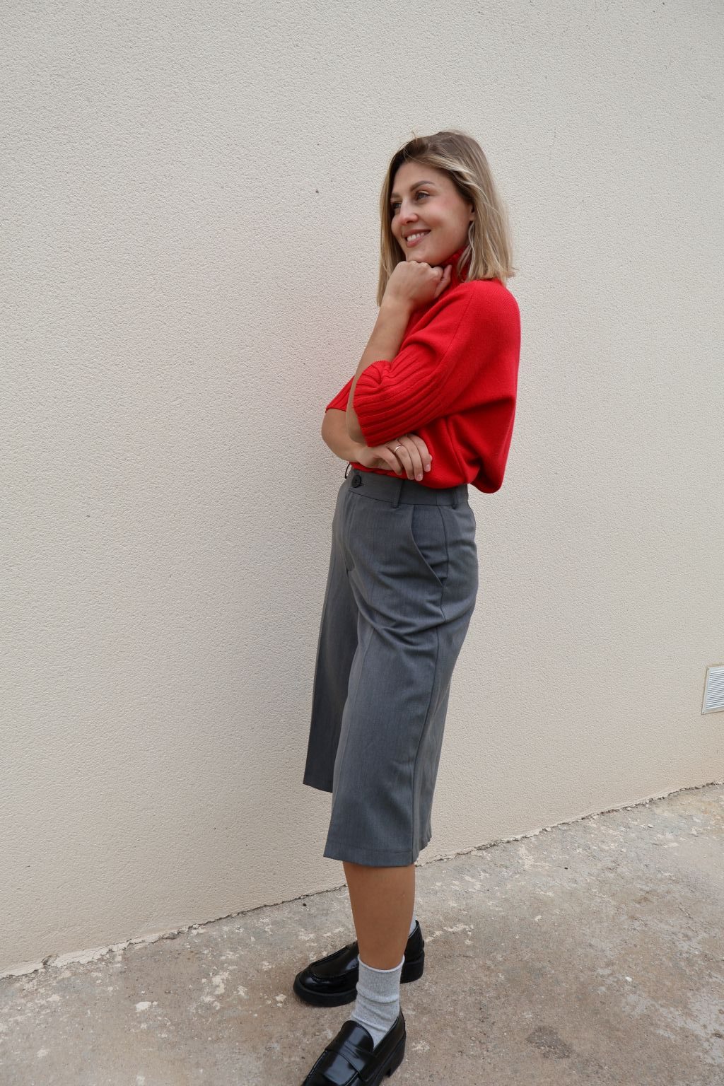 Bermuda gris de mujer PANTTAC de corte ancho, con bolsillos y largo por debajo de la rodilla, combinada con jersey rojo y mocasines negros.